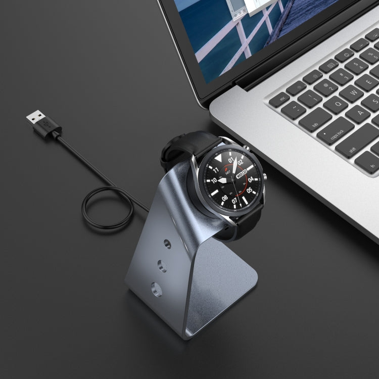Grey aluminum magnetic watch charger stand with USB cable and docked smartwatch