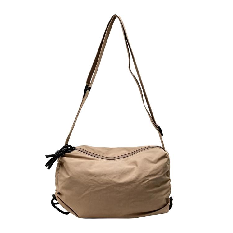 Beige nylon drawstring crossbody bag with adjustable shoulder strap and cinch closure