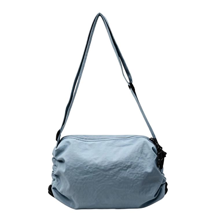 Blue nylon drawstring crossbody bag with adjustable shoulder strap and cinch closure