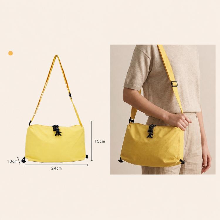 Yellow nylon drawstring crossbody bag worn on shoulder, adjustable strap, cinch closure