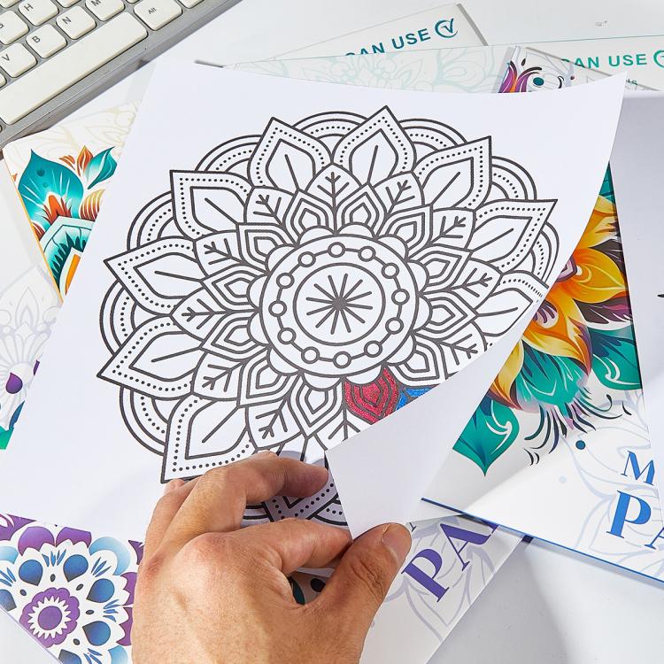 Mandala painting sheets with geometric flower pattern, hands holding one page