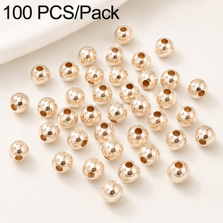 Gold-plated round spacer beads, smooth finish and straight holes; close-up of scattered beads.