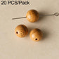 Yellow-beige round seed beads with speckled texture and drilled holes on a pin