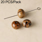 Brown patterned round seed beads with black markings and drilled holes on a pin