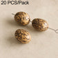 Cream oval seed beads with black speckled lines, strung on metal pins.