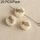 Cream seed beads with engraved characters, with through holes on metal pins.