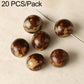 Mottled brown and tan round seed beads with through holes on metal pins.