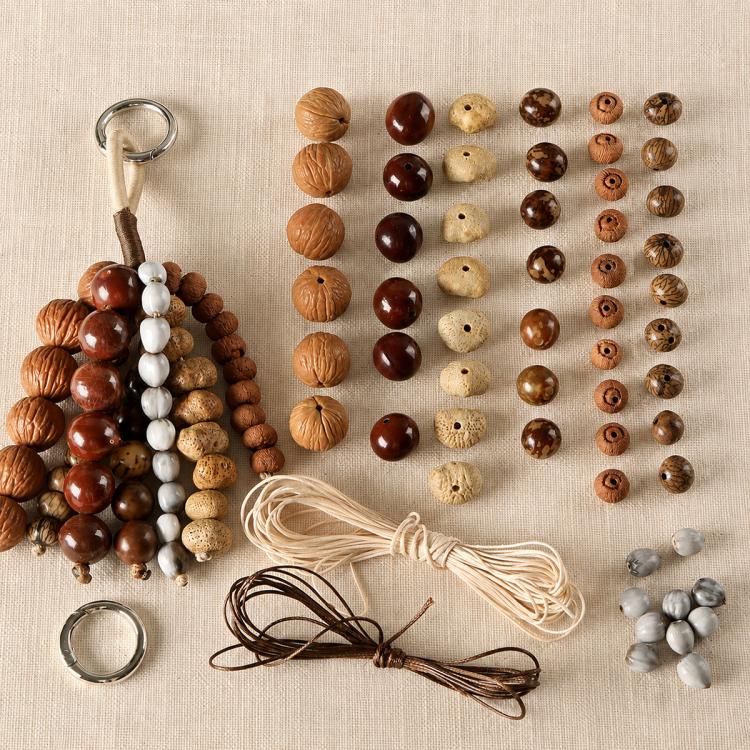Natural seed bead charms set with assorted oval beads, cords, and metal ring