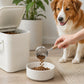 Stainless steel pet food measuring scoop with wooden handle dispensing kibble into bowl