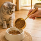 Gold pet food measuring scoop with wooden handle filled with dry kibble