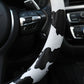 Cow print steering wheel cover grip with black-and-white pattern near control buttons