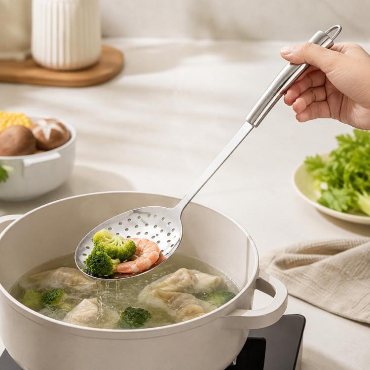 Stainless steel slotted skimmer spoon lifting shrimp and vegetables from boiling water