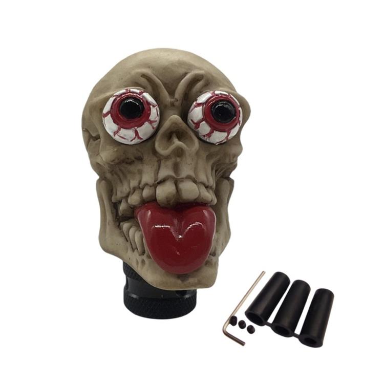 Beige skull-style manual gear shift knob with red tongue and red eyes