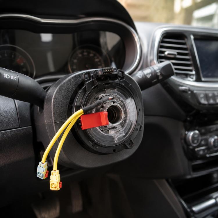 Steering wheel clock spring assembly with yellow wire connectors and red plug, black housing