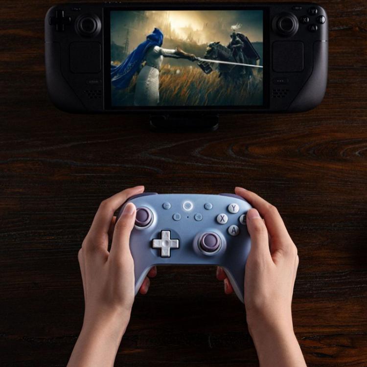 Dark blue wireless game controller held in hands with D-pad, face buttons, and analog sticks