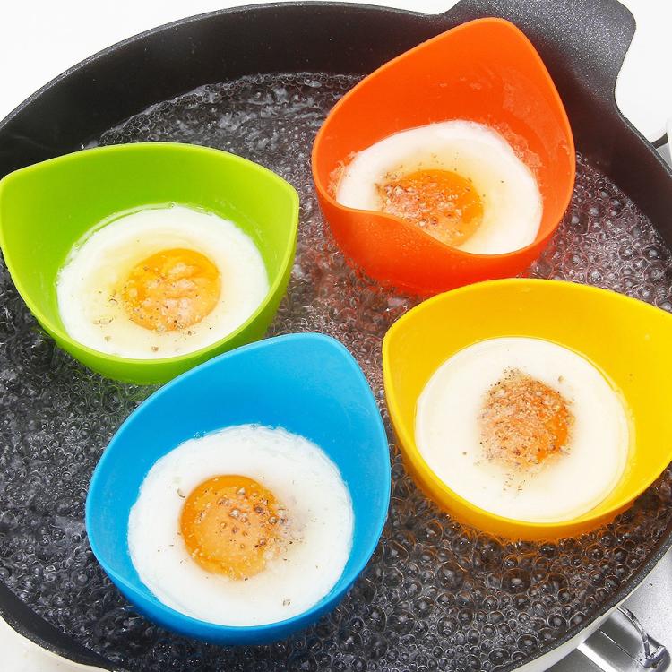 Four colorful silicone egg poacher cups with poached eggs in a skillet