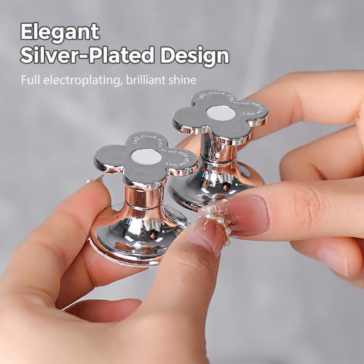 Two flower-shaped silver toilet flush button pushers held in hands