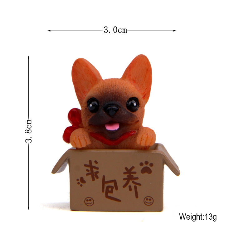 Orange bulldog doll ornament in a brown cardboard box with red bow collar