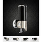 Wall-mounted manual soap dispenser with dark cylindrical bottle and chrome mounting plate