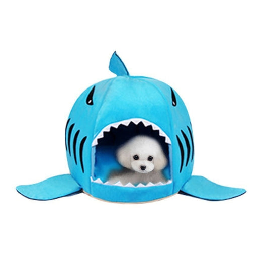 Blue shark-shaped pet sleeping bed nest with open mouth entrance and small white dog inside