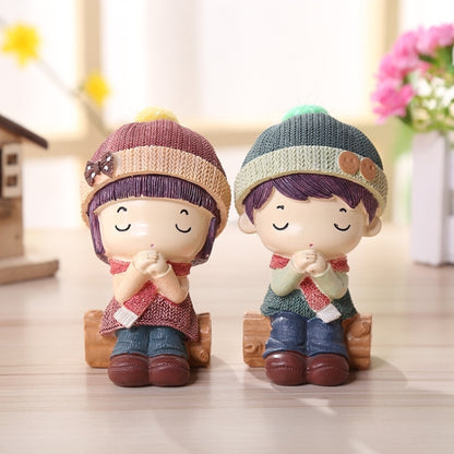 Resin doll figurine pair: two small seated children in knit hats, brown shoes