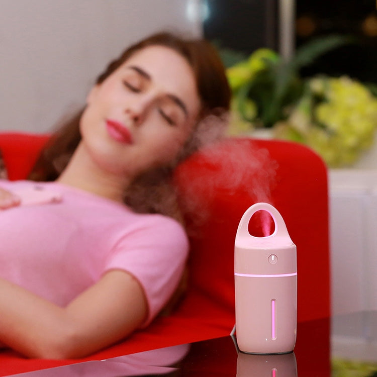 Mini portable humidifier on bedside table, white with blue LED strip and mist