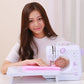 Mini desktop sewing machine in use, hands guiding fabric on the flat extension table