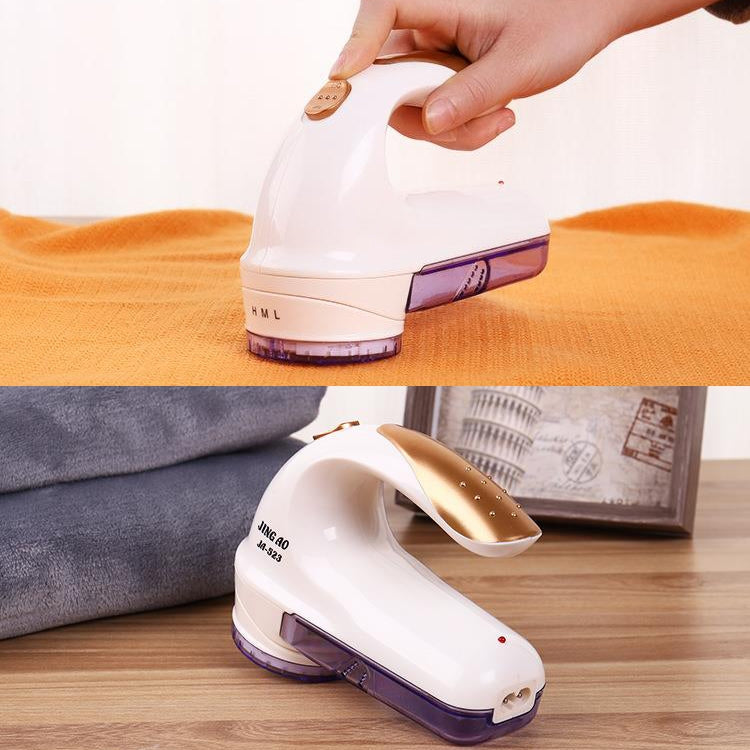 Handheld electric fur ball trimmer removing lint on an orange fabric surface