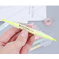 Hand holding a neon yellow double-head highlighter pen with clear barrel