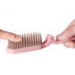 Pink folding hair comb held by hands, compact folded bristles