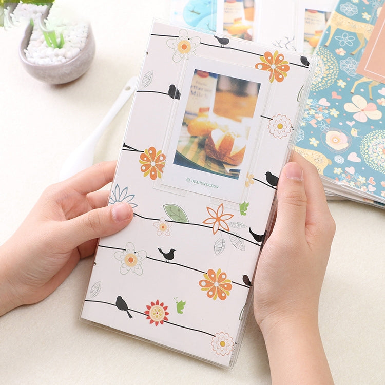 Mini photo album with floral bird pattern cover, white background with orange flowers and birds.