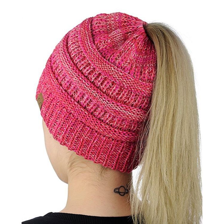 Magenta knitted ponytail cap beanie with ribbed trim and cable-knit swirl pattern