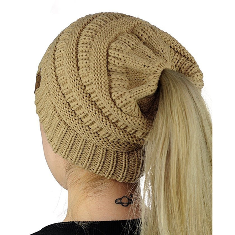Cable-knit ponytail cap beanie in brown, with elastic opening at back for hair.