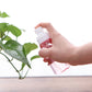 Hand spraying from a refillable transparent bottle with white pump head and pink mist bottle