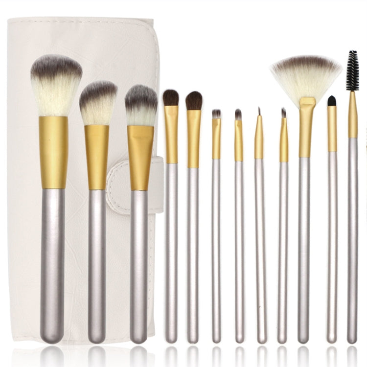 Close-up of beige makeup brush pouch with multiple silver-and-gold brushes lined up