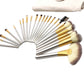 Makeup brush set with silver handles and beige bristles, fanned in a curved layout