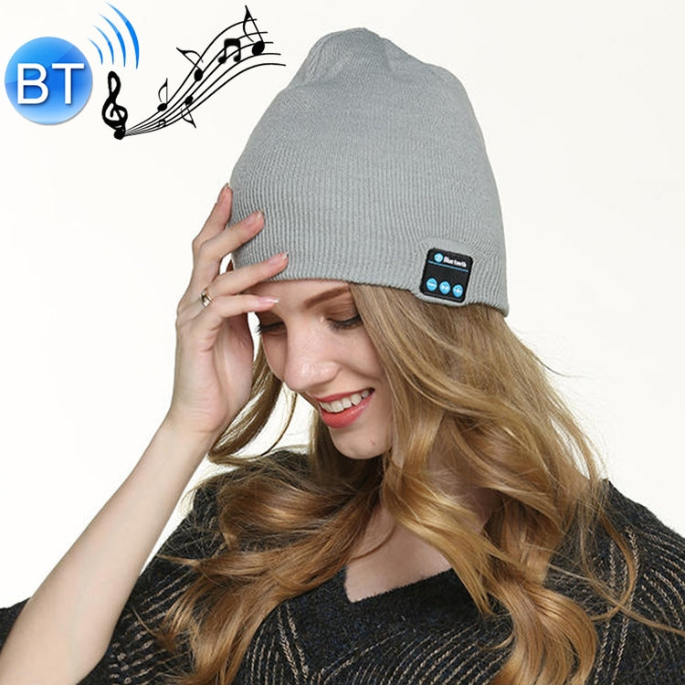 Light gray knit beanie with Bluetooth control panel patch on the cuff, worn by a woman.