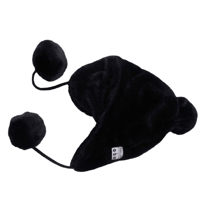 Black plush ear-muff hat with dangling cord, pom-poms, and small button/control panel