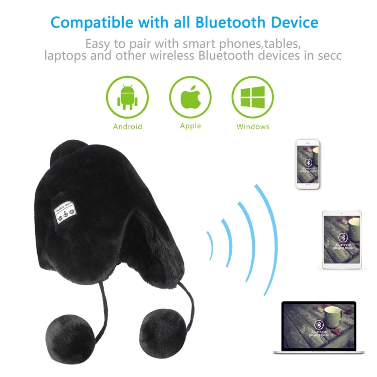 Black plush ear-muff hat with dangling pom-poms and small control panel for Bluetooth
