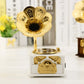 Gold-tone phonograph-style music box on white base with gramophone horn