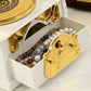 Open white music box compartment with gold-tone front panel and pearl beads