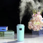 Light blue humidifier cylinder with LED panel and visible mist plume