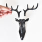 Dark deer head wall hook with four antlers, shown being held up
