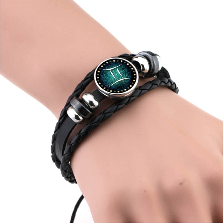 Black braided leather bracelet with round teal constellation charm, crab-like claw glyph, silver clasp