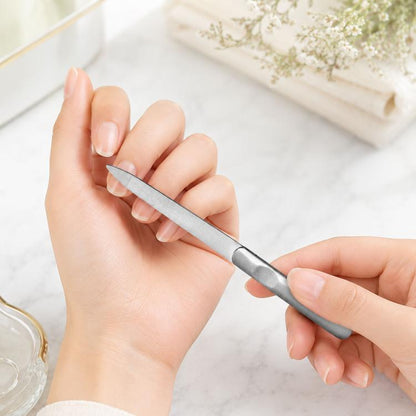 Polished stainless steel nail file with tapered tip, held between fingers