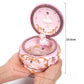 Pink rotating music box with ballerina stand; open lid shown in hand