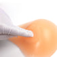 Left silicone breast pad being inserted by a gloved hand, beige postoperative prosthesis