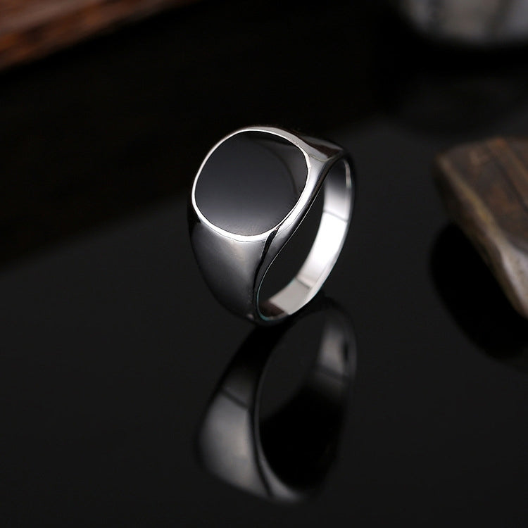 Silver-tone drip signet ring, black oval face, angled view