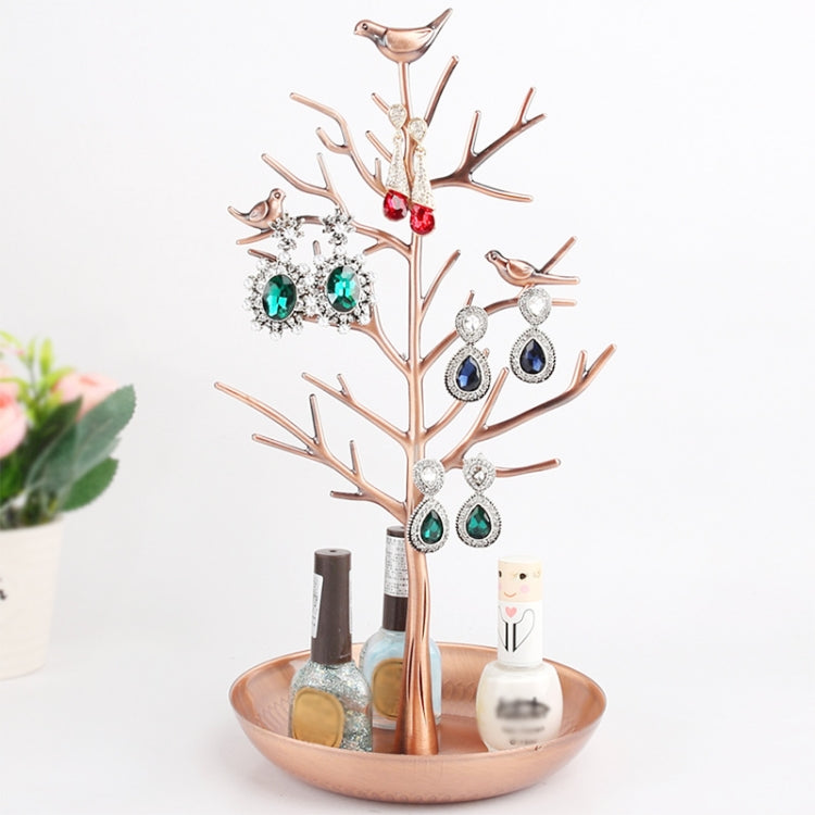 Rose gold tree jewelry stand holding dangling earrings with blue, red, and green stones
