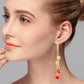 Gold-tone crystal tassel earrings with red drop beads and clear accents